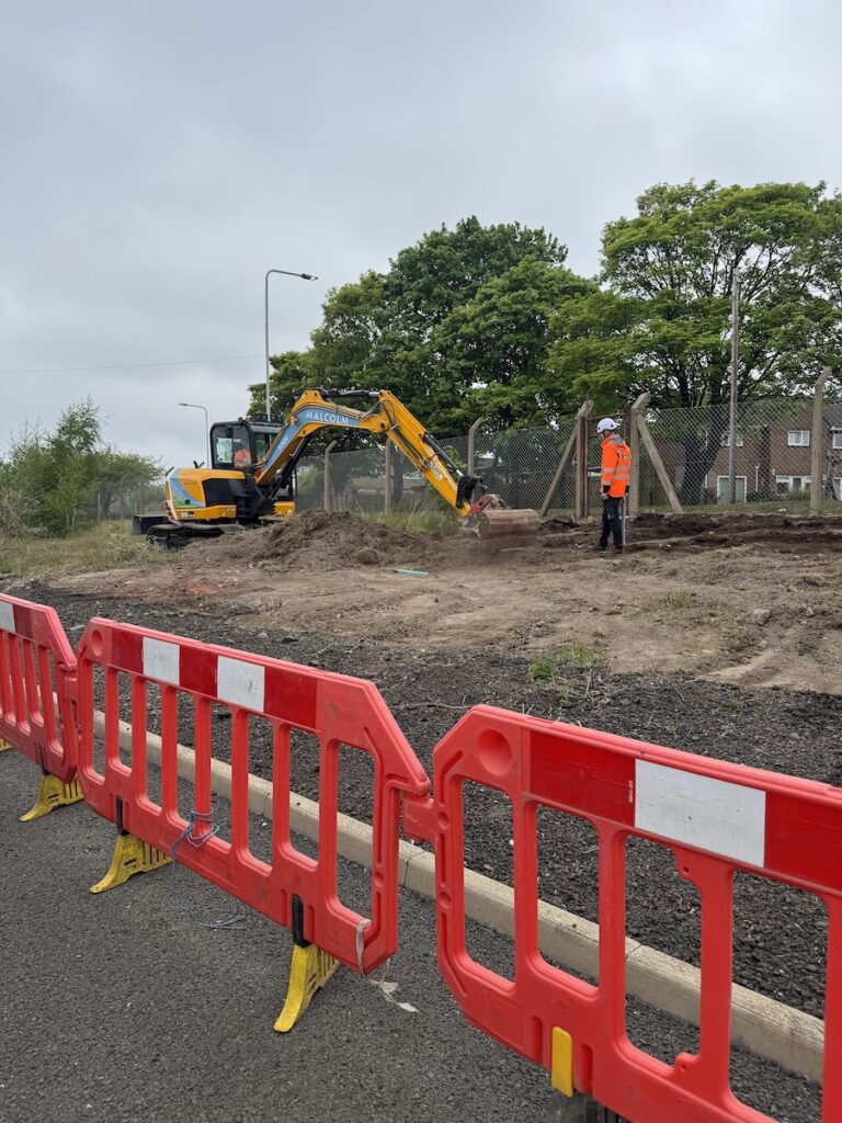 JCB carrying out land reinstatement at a commercial site with a JBB team member supervising in the background.
