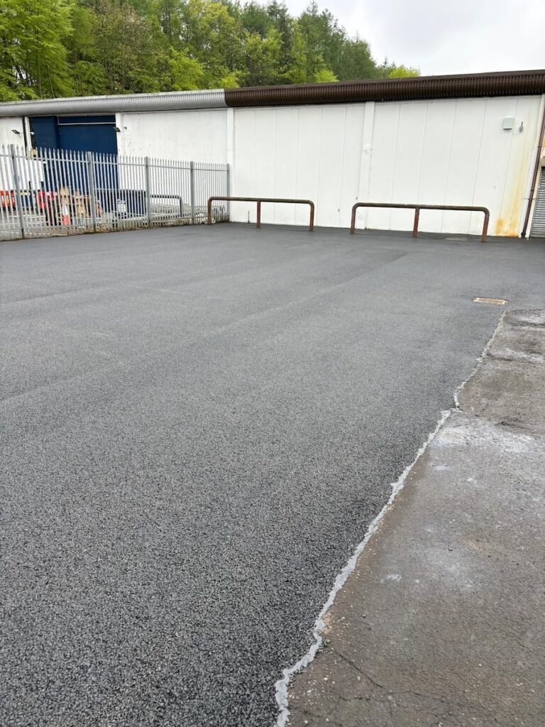 Freshly repaired tarmac surface at a commercial site following invasive weed treatment.